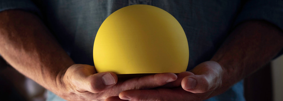 Hands holding a yellow porcelain wind chime form